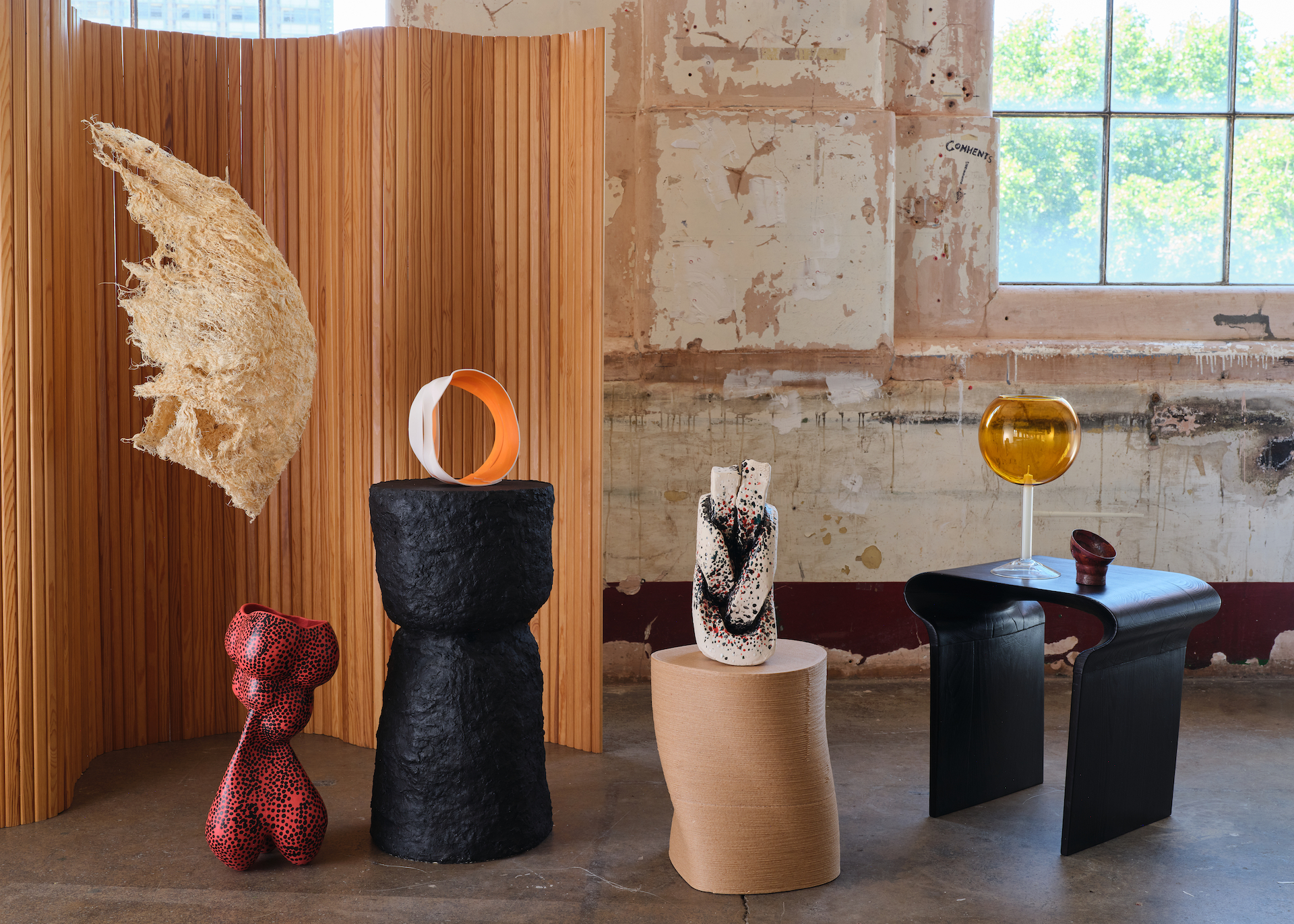 A number of craft items in a lifestyle setting including ceramics, glass, metal and a hanging mobile made from grass root