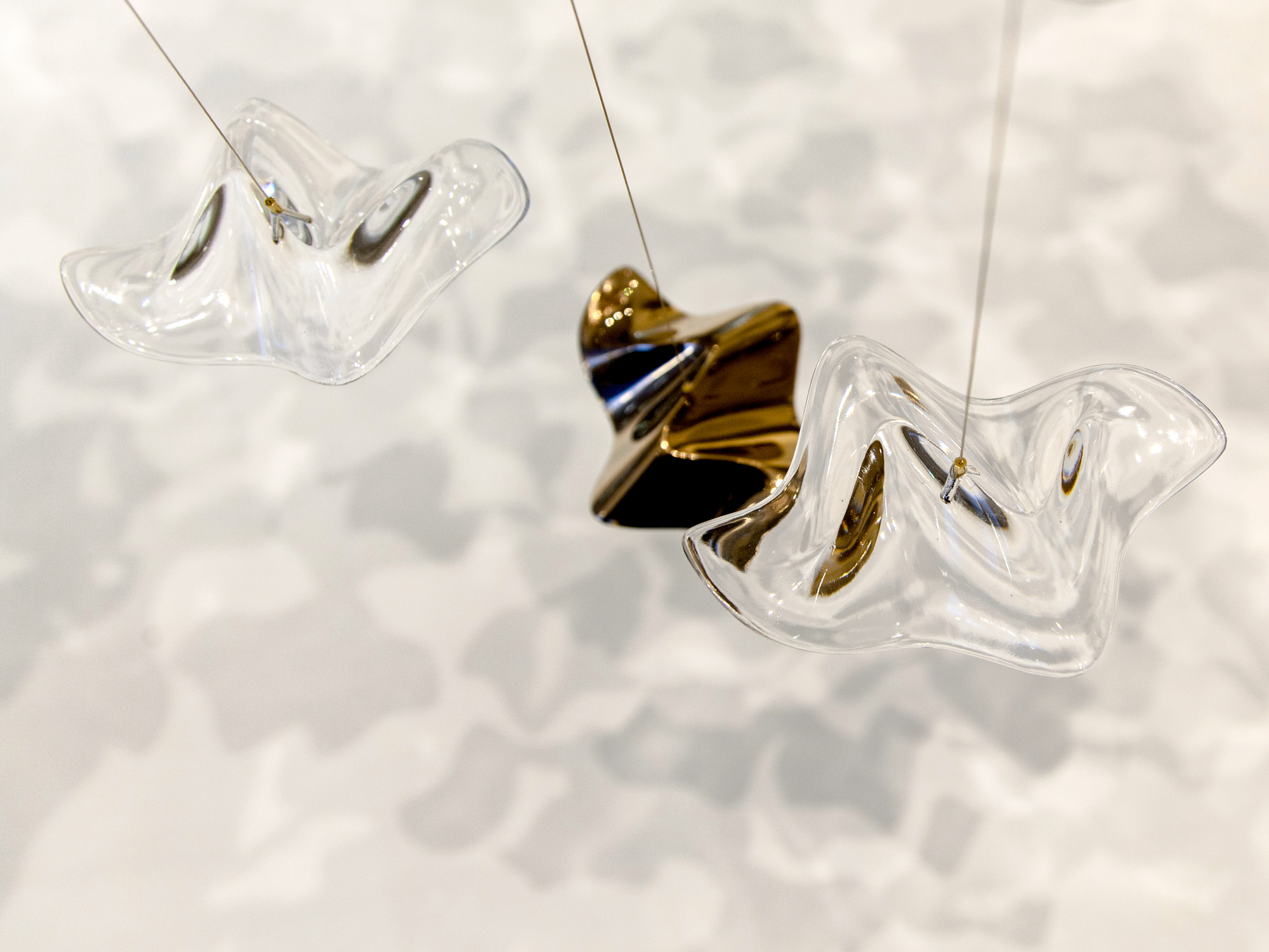Clear crystal and gold plated "Sand & Sea" ripples creating reflections and refractions on a white floor.