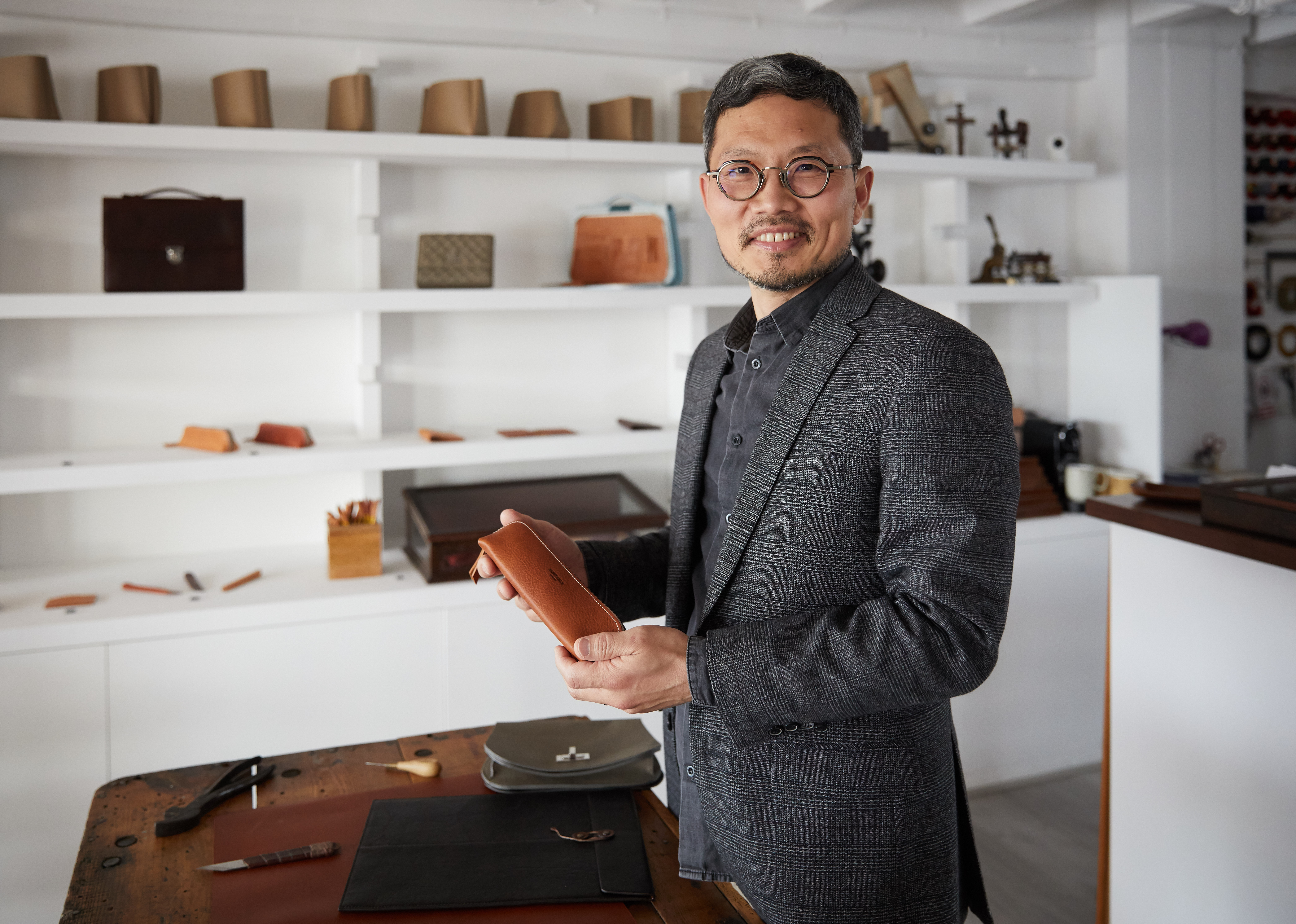 John from Montable Leather Studio, standing in his workshop at Oxo, holding a handmade leather pouch