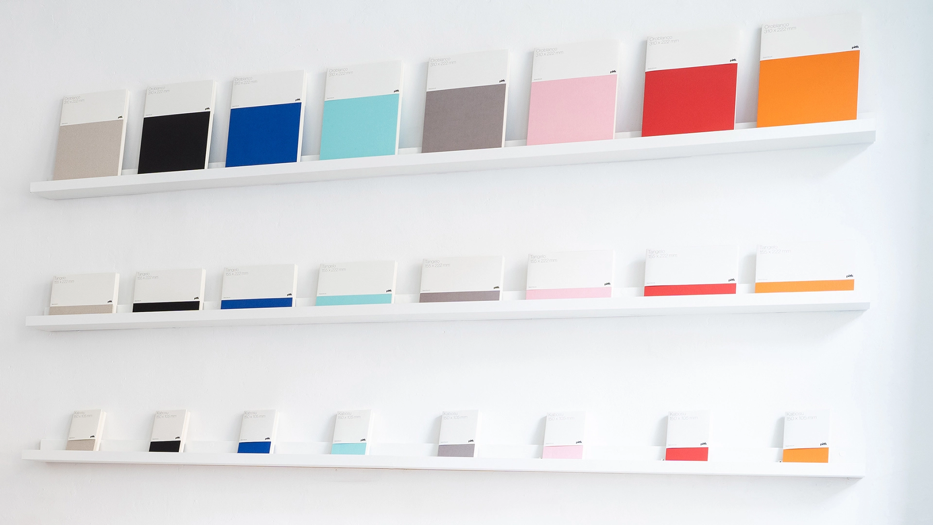 Colourful sketchbooks fill a wall in varying sizes