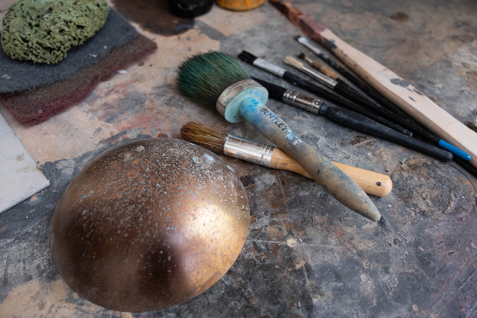 Tools next to small brass pendant to show patination process