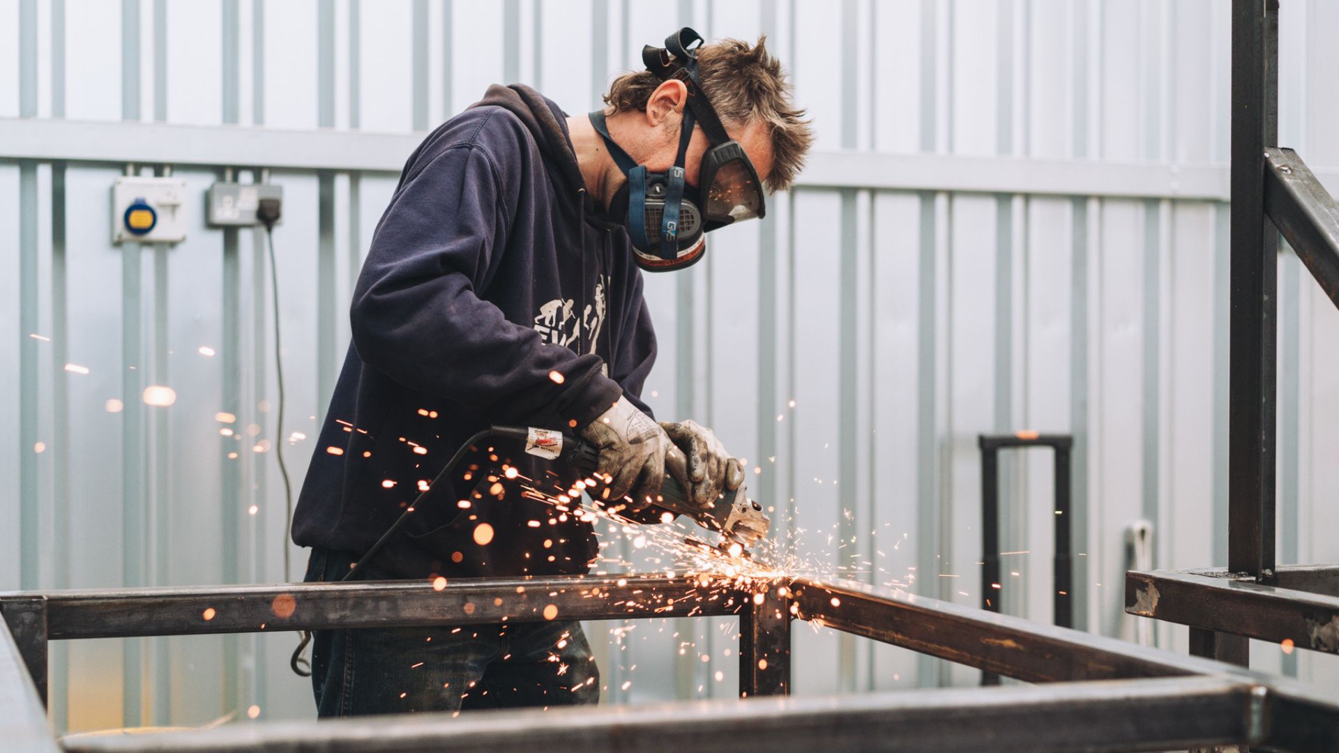 Man uses angle grinder at BLOQS London Metal Works