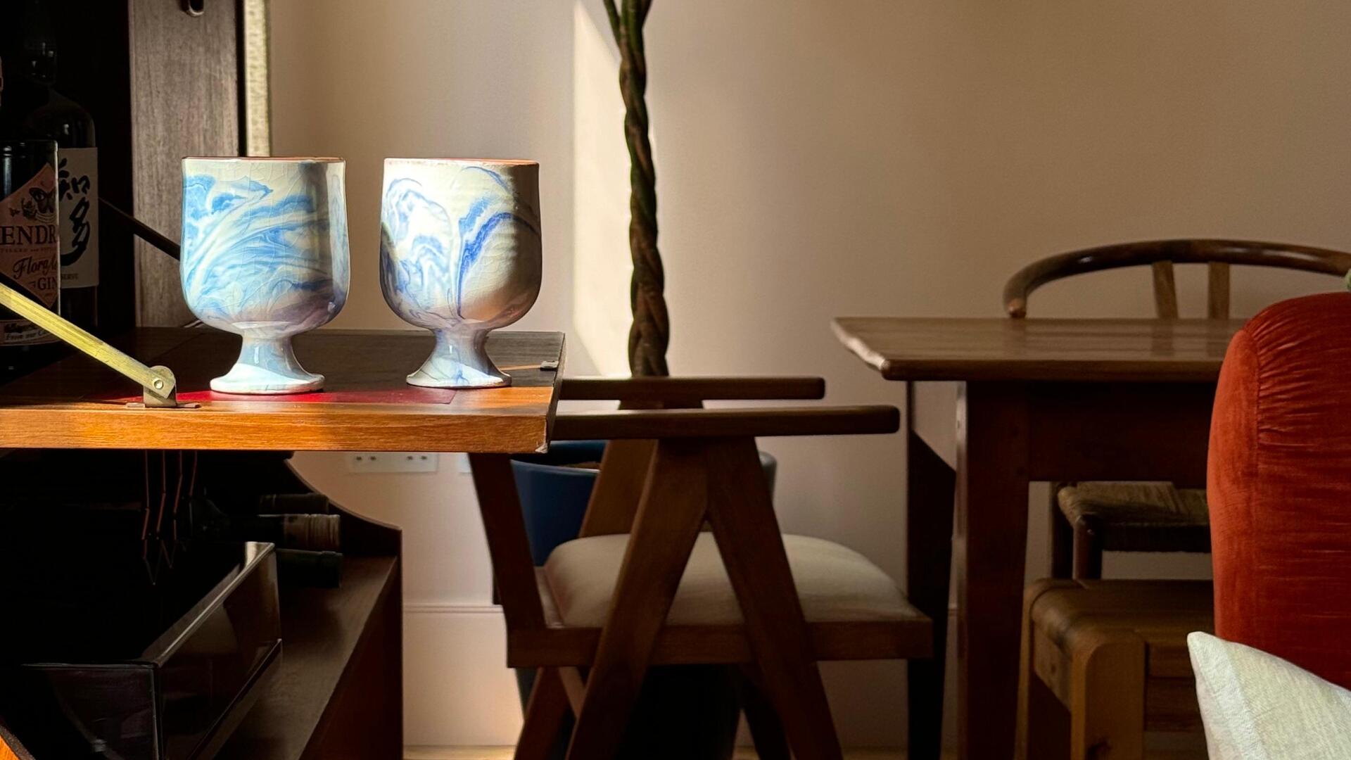 Two Nebula cups on a wooden dining table in a sunlit dining room.