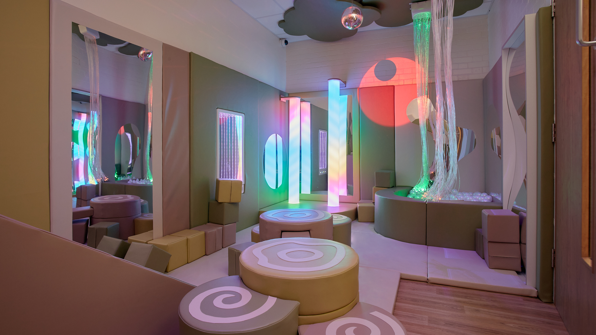 A soft padded room with play equipment and sensory lighting.