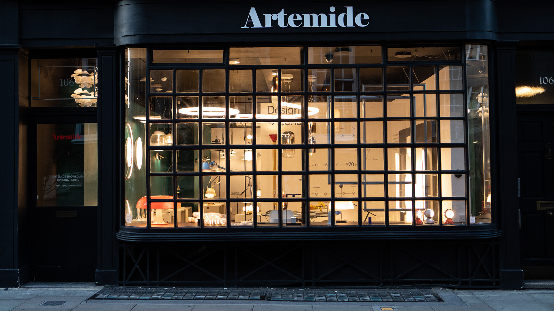 Exterior of the Artemide London showroom at night, with illuminated displays visible through the large windows.