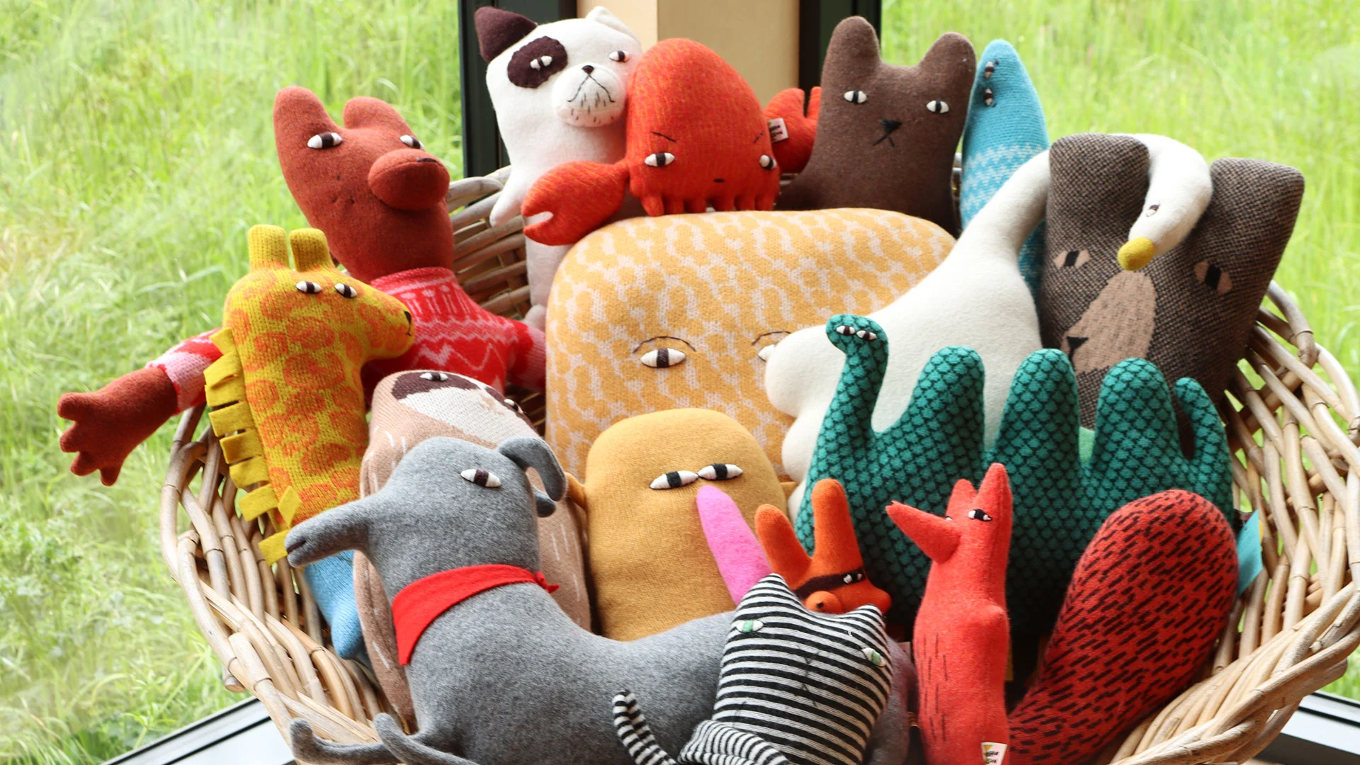 A big basketful of colourful knitted creatures.