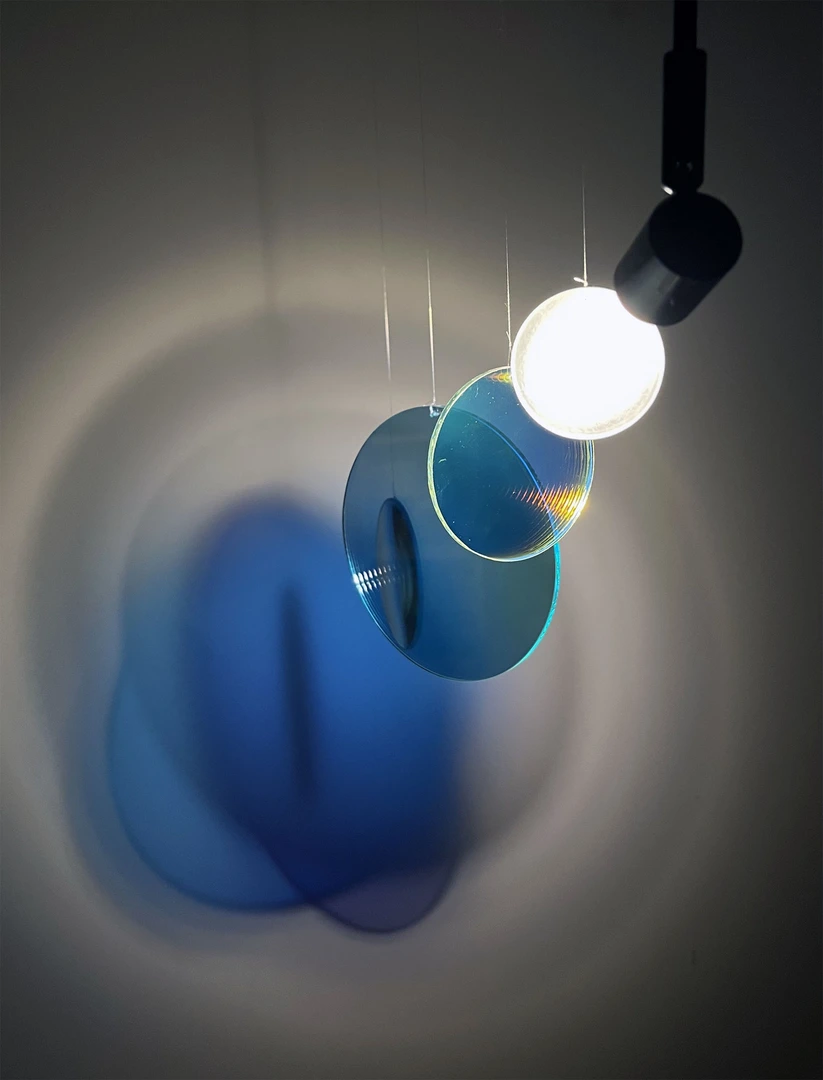 Light casts coloured shadows through glass blue lenses suspended