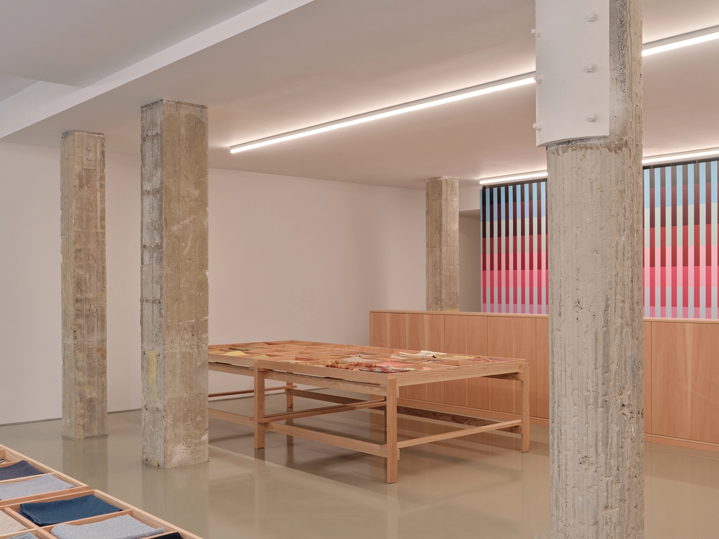 Maharam showroom interior view with wooden display table and colorful artwork in background.