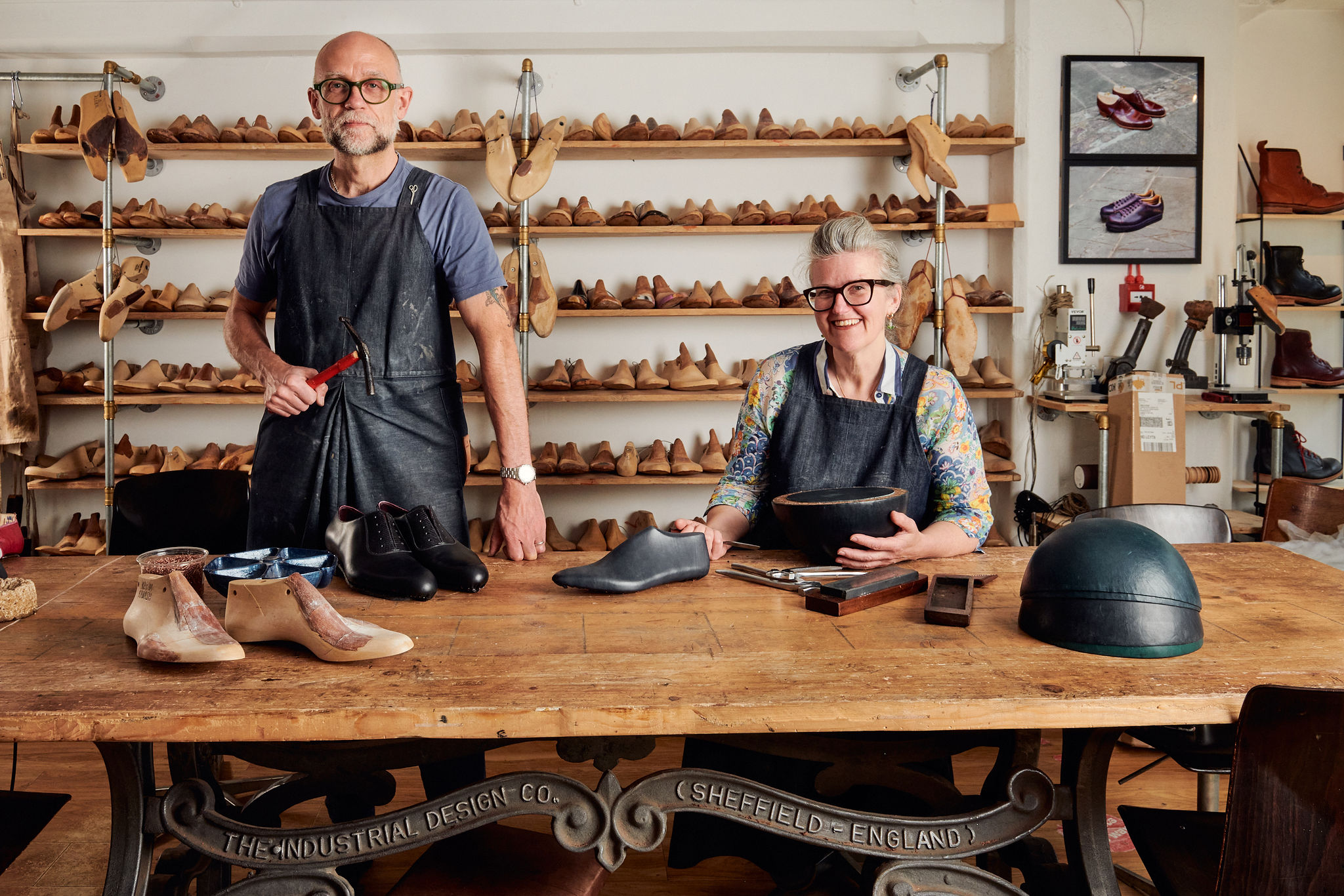 Image of a man and a woman posing in front of a table of shoes.