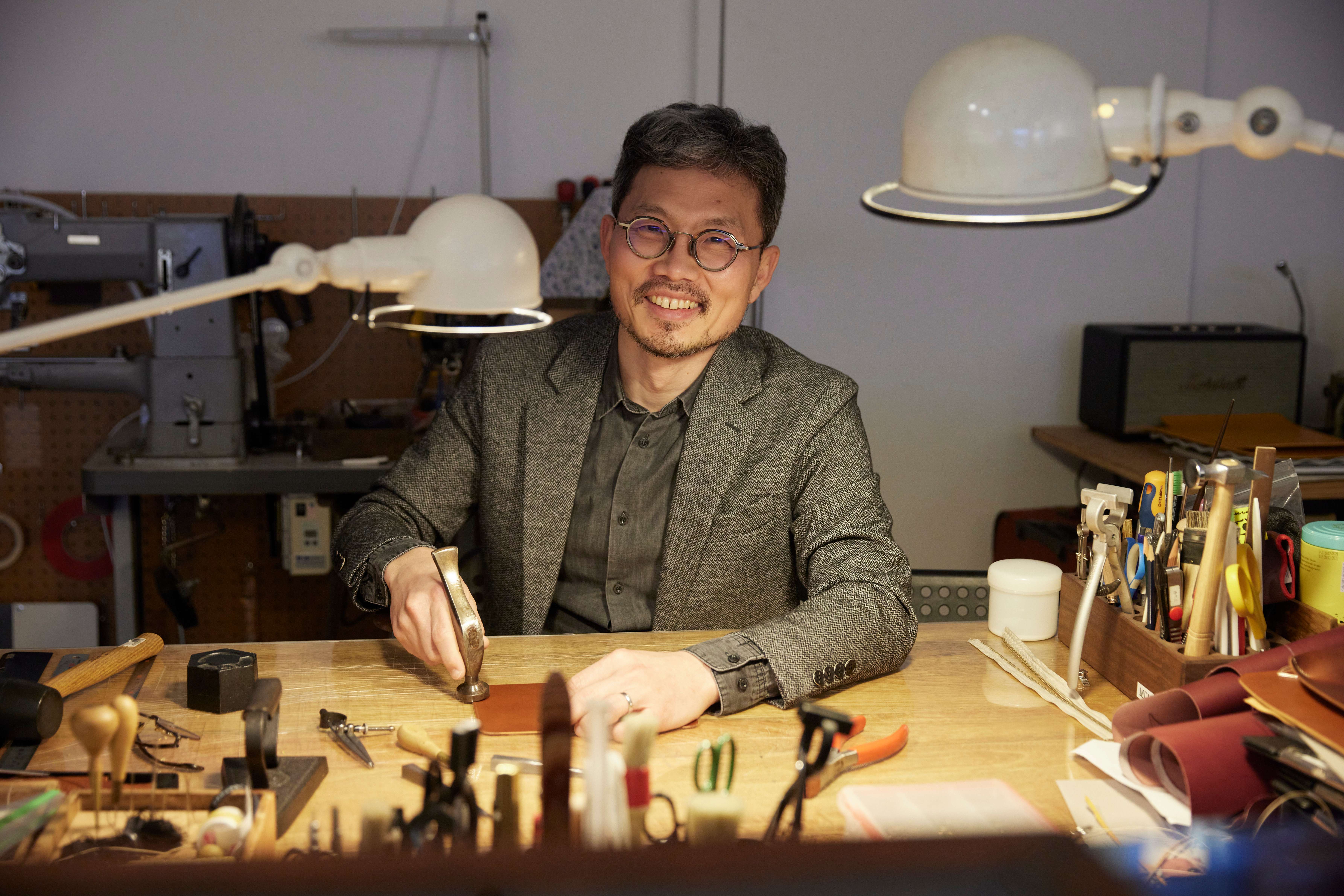 Image of a man posing at a table in his workshop.