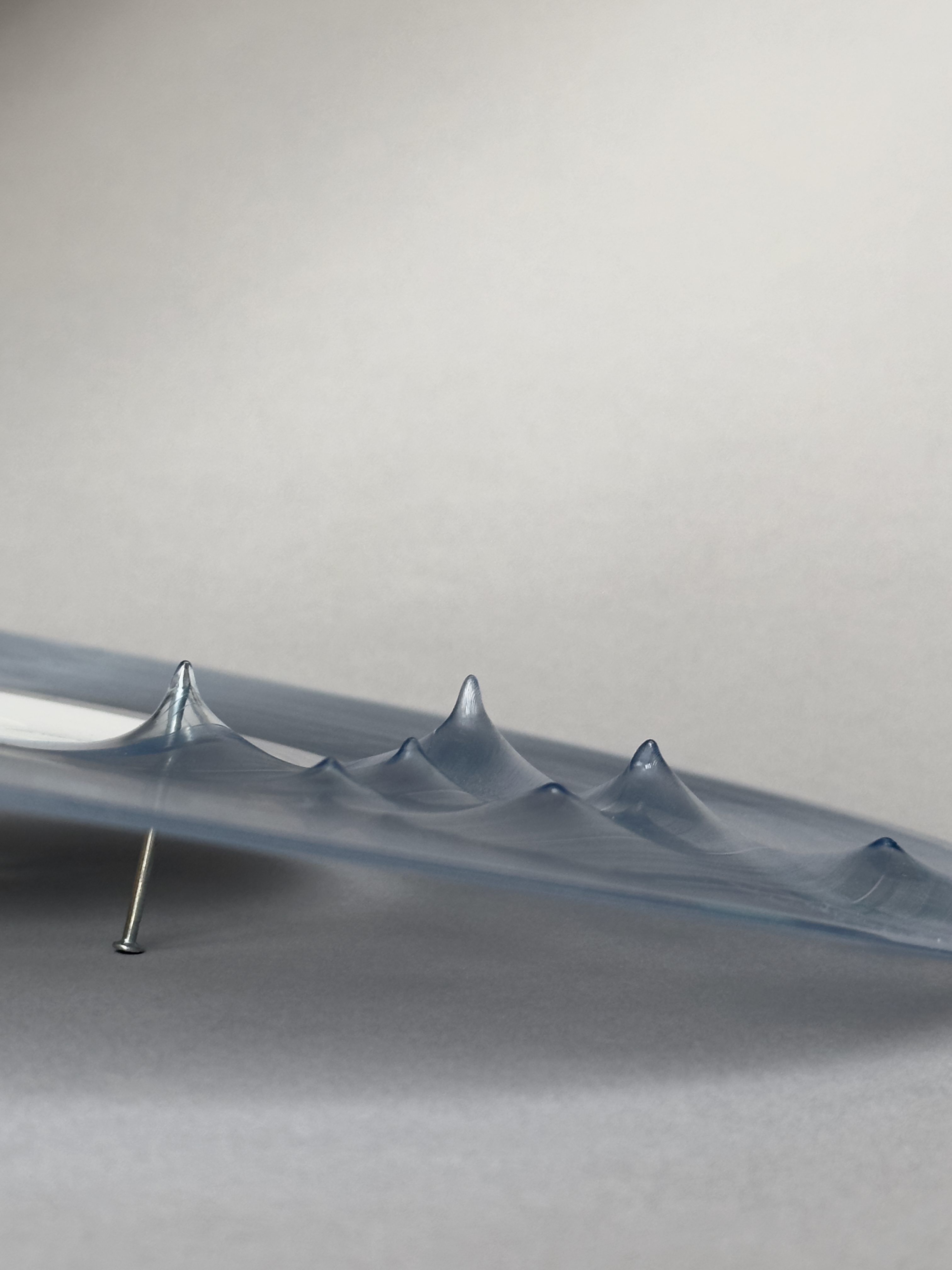 Close-up of a warped vinyl record, punctured by a nail.