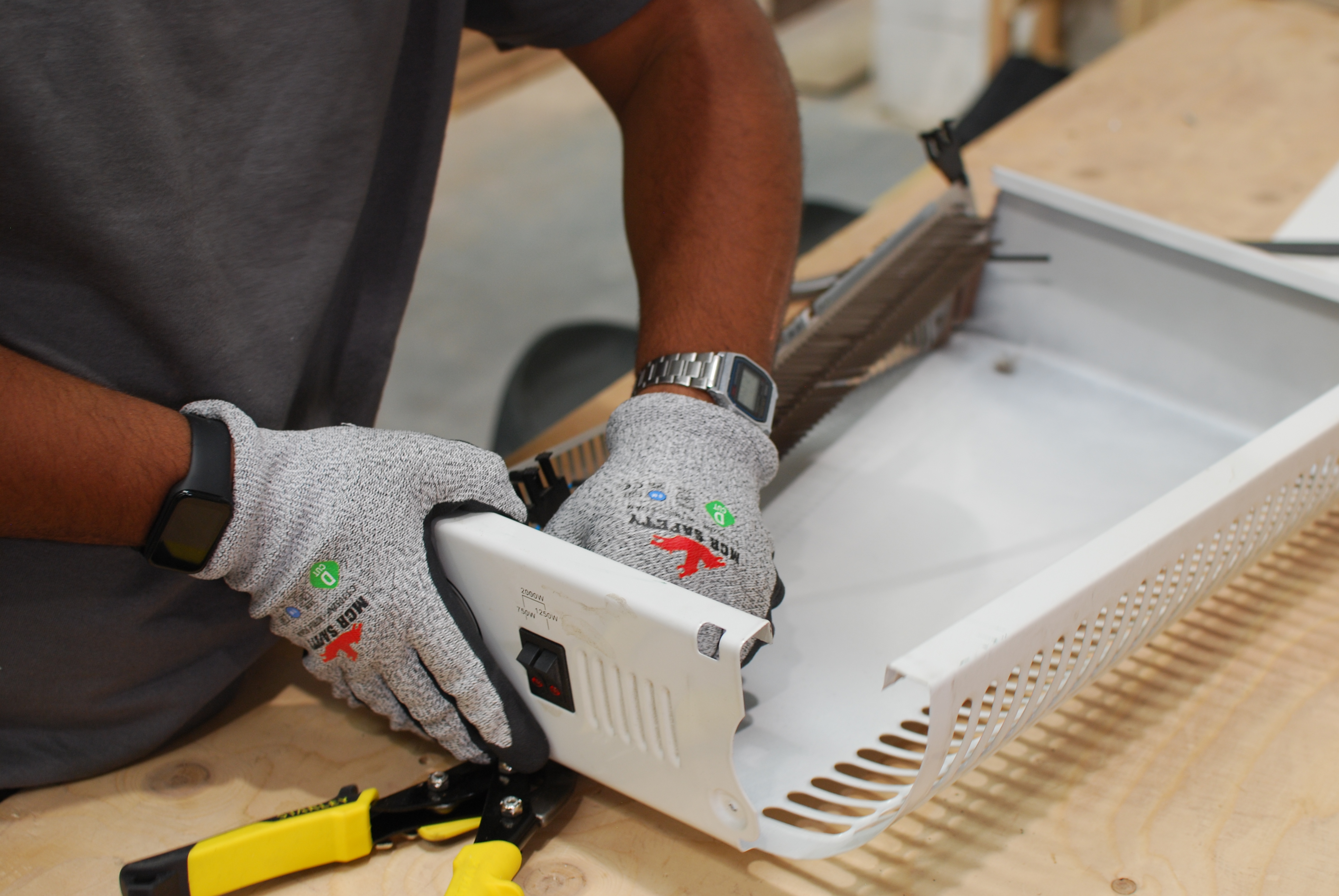 A young person wearing safety gloves dismantles a discarded electric radiator, to reuse the metal.