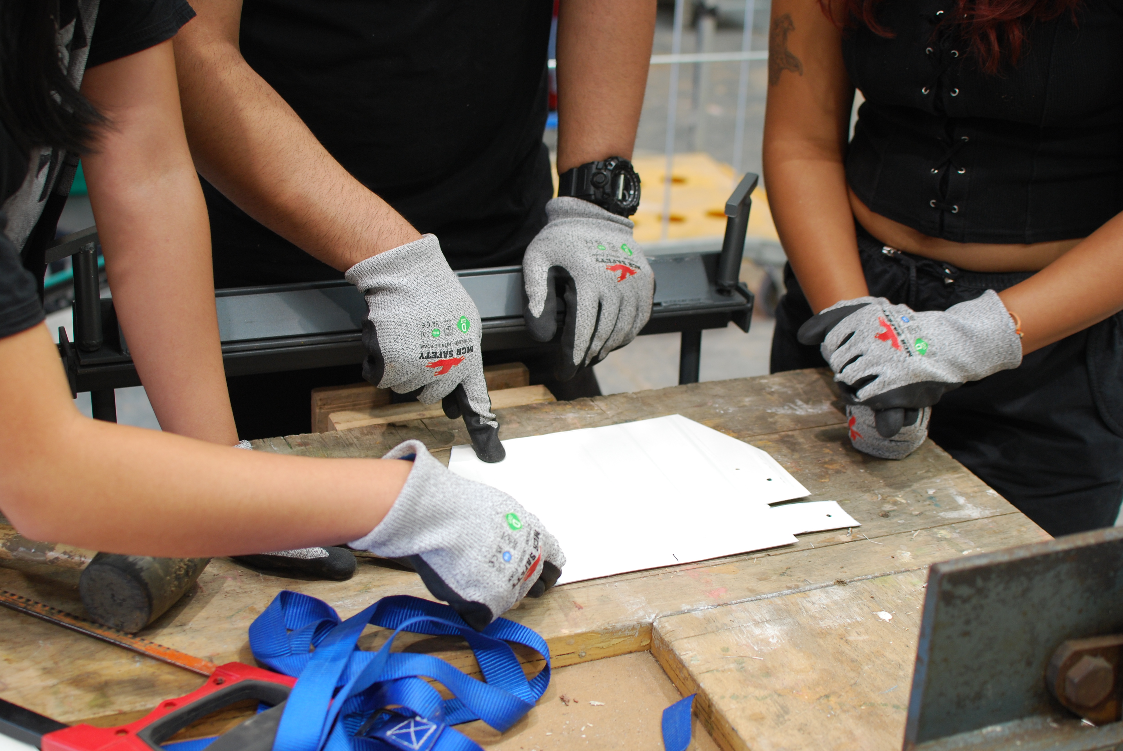 A group of young people discuss the dustpan template they've cut out of scrap metal. 
