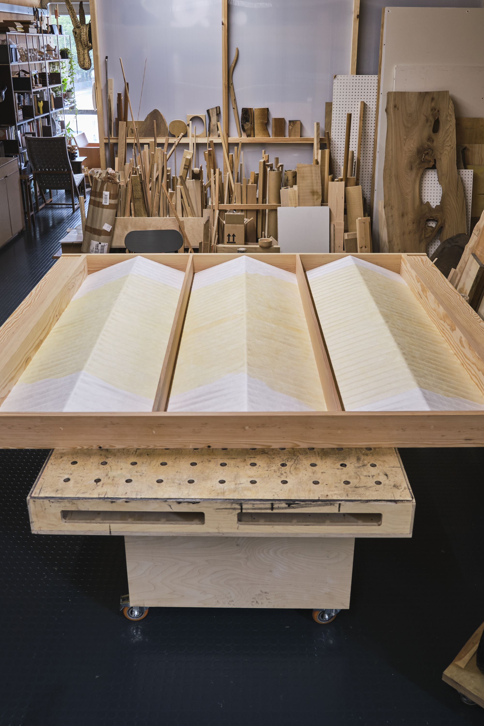 A panel of corrugated stretched tyvek painted in yellow and white on a work bench in a studio