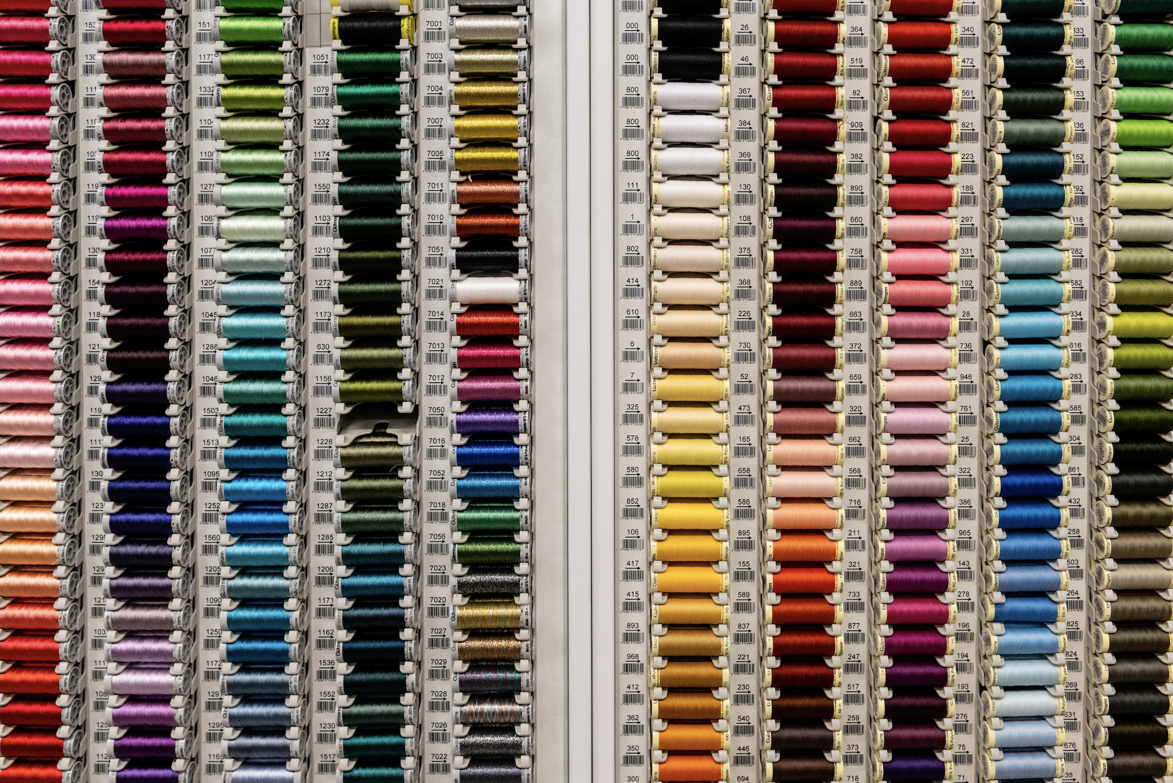Colourful sewing thread arranged in columns in a white stand