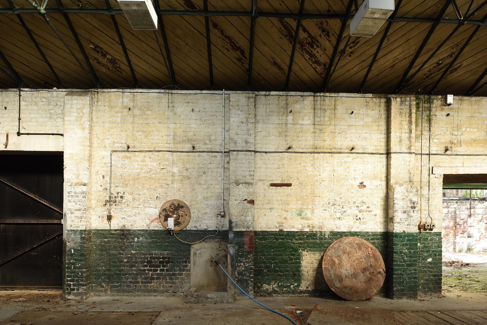 Photograph of derelict industrial interior with white and green painted brickwork